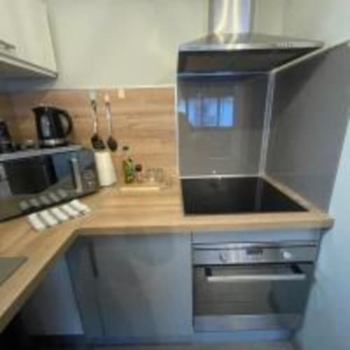 Cuisine contemporaine de l'appartement de Perpignan avec appareils en acier inoxydable, plan de travail en bois et accès balcon vue sur ville