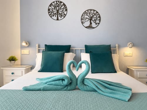 Luxurious bedroom at Apartamentos El Calón Playa with twin beds, turquoise towel swans, and sea view decor in Cuevas del