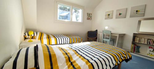 Chambre lumineuse de la villa Mer et Maisons avec lits jumeaux, literie rayée jaune et bleu marine, vue sur le jardin