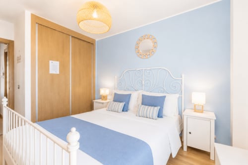 Chambre lumineuse aux murs bleus, tête de lit en métal blanc et oreillers rayés à Sara & Gino Fuerteventura à Corralejo