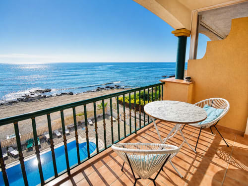 Beachfront apartment balcony in Cuevas del Almanzora with sea view, white furniture, and Mediterranean coastline