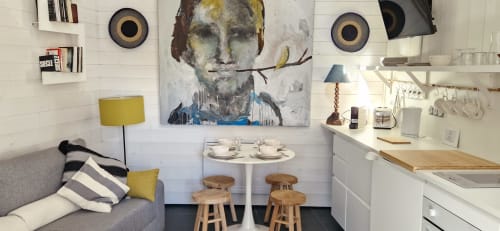 Cuisine studio moderne et séjour aux Chambres du Keriolet avec canapé gris, tabourets bois et art contemporain