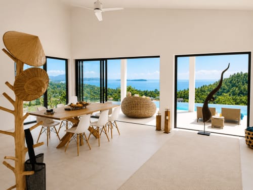 Modern villa dining area with sea views overlooking Ko Samui, Thailand, featuring wooden furniture and infinity pool terrace