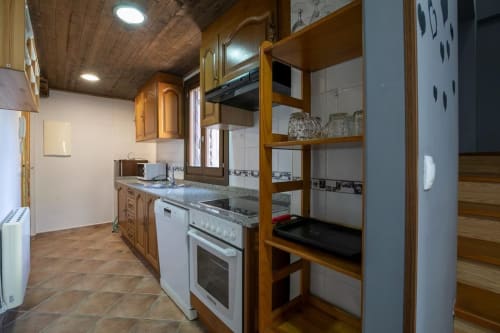 Cocina del apartamento de montaña en Montgat con armarios de madera, electrodomésticos blancos y estantes para comedor