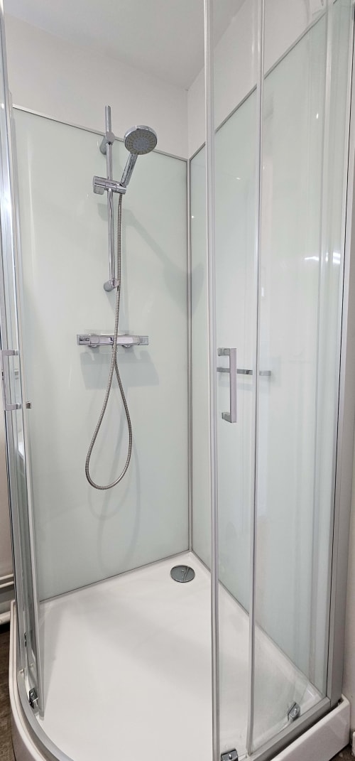 Douche moderne avec pommeau de pluie et douchette à main dans un appartement de Saint-Valery-en-Caux
