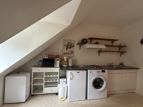 Kitchenette mansardée équipée d'un lave-linge, micro-ondes, réfrigérateur, cuisinière et rangements à Hébergement Luxeuil Les Bains