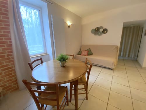 Séjour du gîte Le Cocon avec table à manger, canapé crème et grande fenêtre à Le Cocon De Curson, Chanos-Curson