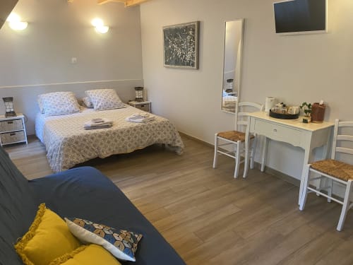 Spacieuse chambre de la maison d'hôtes Le Cocon De Curson avec lit, coiffeuse blanche, TV et vue sur le jardin à Chanos-Curson