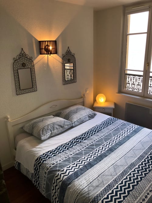 Chambre cosy du Paillot de Montabert à Troyes, avec parure de lit à motifs, miroirs décoratifs, éclairage chaleureux et vue sur la ville