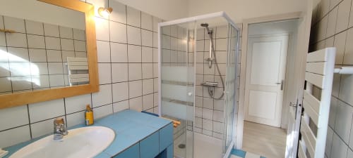 Salle de bain moderne de la villa Mer et Maisons à La Trinité sur Mer avec vanité bleue, douche vitrée et murs carrelés