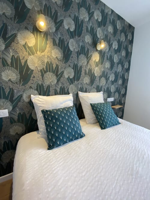 Chambre moderne à La Maison Blanche avec papier peint botanique, literie blanche, coussins bleu canard motifs et appliques murales chaleureuses