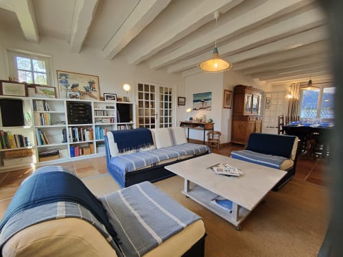 Spacieux salon de villa chez Mer et Maisons avec sièges à rayures bleues, bibliothèque blanche et plafond aux poutres apparentes, La Trinité