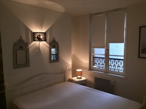 Chambre élégante de l'appartement Le Charmant Zola à Troyes avec lit blanc, miroirs décoratifs, éclairage moderne et vue sur la ville