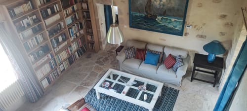 Salon cosy avec bibliothèque, canapé, luminaire suspendu et vue sur le jardin à Magnanerie de Sainte Croix