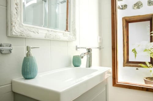 Baño moderno con lavamanos blanco, accesorios turquesa y espejo enmarcado en Casa 1820, La Palma Rural