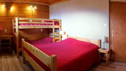 Cozy bedroom with wooden furnishings, red bedding, bunk beds, and warm lighting at Chalet La Louvière
