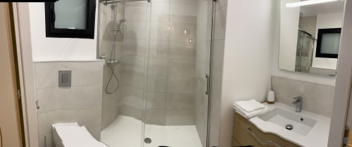 Modern bathroom with walk-in shower, vanity sink, and white towels at La Maison Blanche B&B in Bouguenais