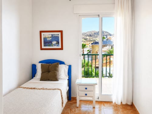 Bright bedroom with blue bed and sea view balcony at Apartamentos El Calón Playa, Cuevas del Almanzora