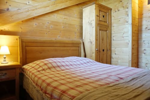 Cozy wood cabin bedroom at Chalet La Louvière with red plaid bedding, wooden furniture, and mountain lodge ambiance in