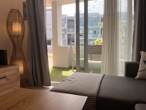Modern bedroom at FTV Holidays Homes in Corralejo with glass balcony doors, contemporary decor, and views of neighboring