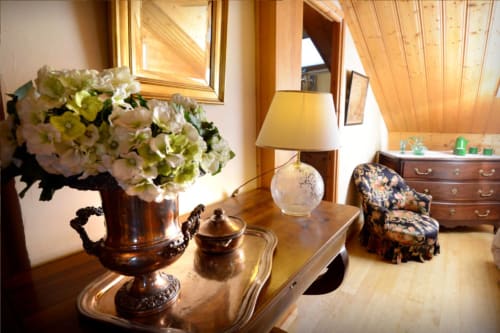 Chambre élégante de l'Auberge Nemoz avec hortensias, mobilier ancien et vue sur les montagnes à travers un plafond en bois
