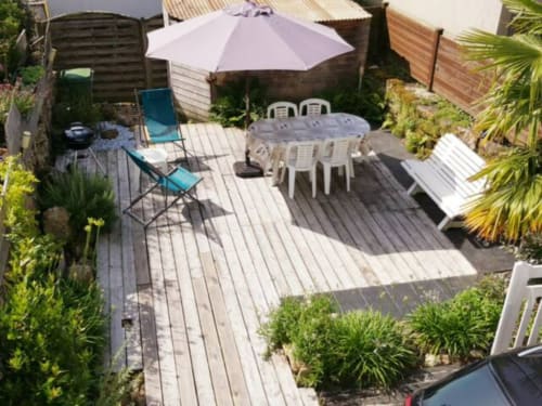 Terrasse de jardin de la villa Mer et Maisons à La Trinité sur Mer avec table à manger, parasol, transats et plantes tropicales