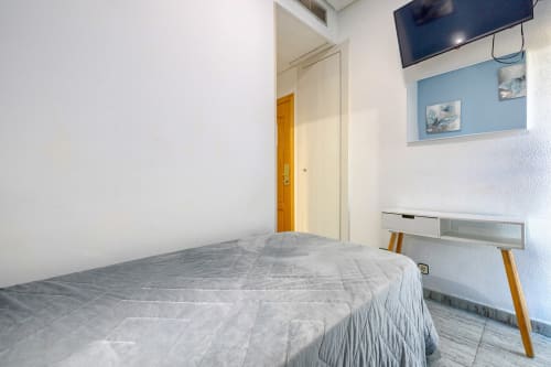 Habitación luminosa en Hostal El Molino con cama individual, escritorio, TV y pared azul en Collado Villalba