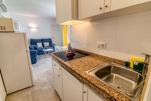 Cocina moderna con encimera de granito, fregadero y electrodomésticos de acero inoxidable que abre a la sala de estar con sofá azul en Las