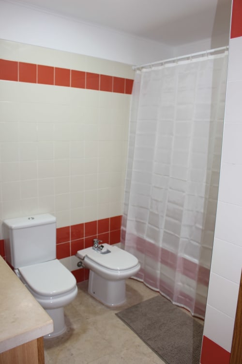 Modern bathroom with red and white tile design, toilet, bidet, and shower curtain at Seahorse House, Tavra