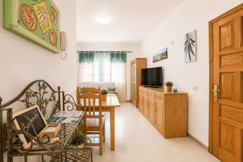 Salon lumineux à Corralejo avec mobilier en bois, TV, table à manger et charme côtier