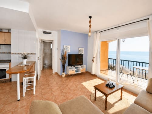 Bright sea-view apartment with blue accent wall, terracotta tiles, modern kitchen, living area, and ocean balcony at