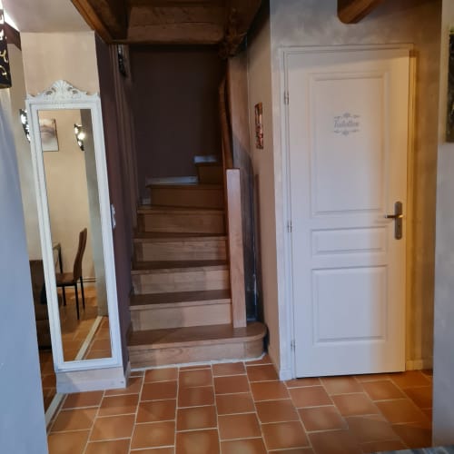 Interne houten trap van Gîte Cristal naar de bovenverdieping met aparte bedden en slaapbank.