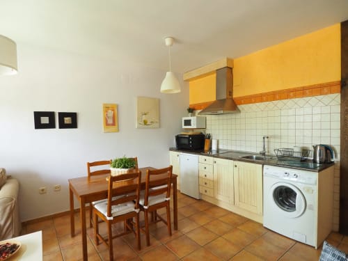Cocina y comedor modernos en apartamento rural cerca de Sebúlcor, España, con armarios amarillos, mesa de comedor y electrodomésticos