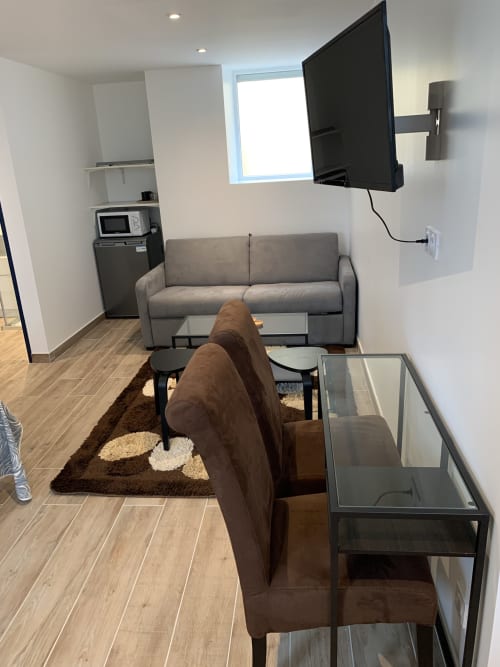 Studio moderne au Restaurant du Port avec canapé gris, fauteuil marron, TV et kitchenette à Saint Pierre de Boeuf