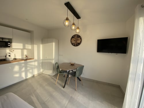 Studio moderne à La Maison Blanche avec table à manger, cuisine, suspensions et TV murale à Bouguenais