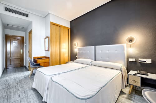 Habitación moderna del Hostal El Molino con camas gemelas, pared de acento oscuro e iluminación contemporánea