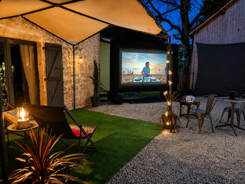 Cinéma en plein air en soirée au Domaine Valenquercy avec terrasse privée, chaises longues et film sur écran en jardin