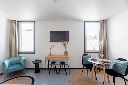 Apartamento estúdio moderno no Porto com área de estar, TV, escrivaninha de madeira e vista para a cidade pelas grandes janelas