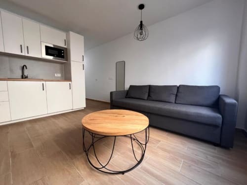 Moderna sala de estar en Rural La Palma con kitchenette, sofá oscuro, mesa redonda de madera y vistas a la ciudad