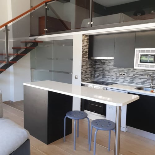 Cocina moderna con barra de desayuno en el apartamento Hostal El Molino de Collado Villalba, equipada con electrodomésticos de acero inoxidable y