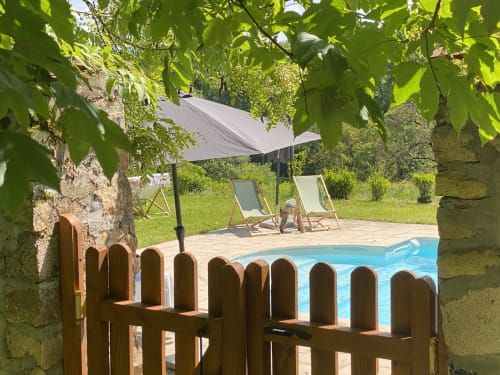 Jardin du Château de Vaux Morvan avec piscine, clôture bois, transats, pergola ombragée et verdure luxuriante