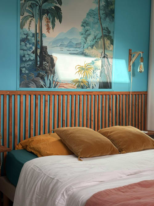 Chambre tropicale à La Villa Maraloupia avec lit en bois, coussins dorés et fresque de jungle offrant vue sur la mer
