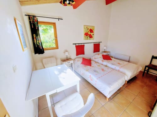 Bright bedroom with two single beds, red accents, and garden view at Les Gites de Campardon, Monties