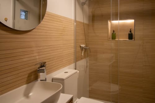 Modernes Badezimmer im Loft La Fragua de Setenil mit Holzwänden, Glassdusche, Waschbecken, Toilette und beleuchtetem Regalnische