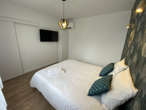 Chambre moderne à La Maison Blanche B&B à Bouguenais avec lit blanc, TV murale, éclairage suspendu et mur texturé
