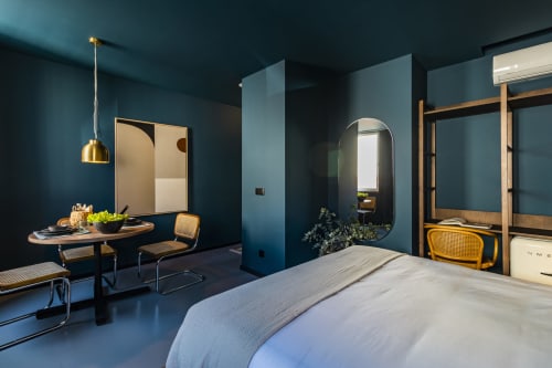 Moderno estúdio em hotel Porto com paredes verde-azulado, cama, área de refeições e acabamentos dourados