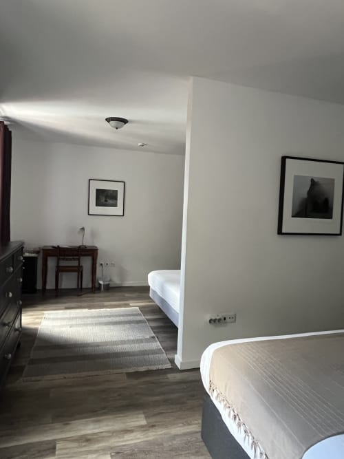 Quarto moderno no Rum Inn II na Madeira com camas duplas, piso de madeira, área de estar e quadros emoldurados em parede branca