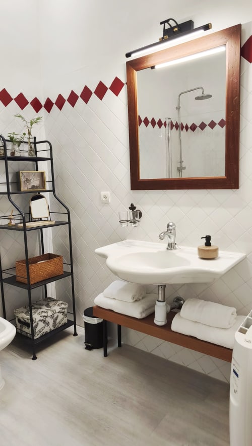 Baño moderno en apartamento Mirador Medieval, Cáceres, con azulejos blancos y detalles en diamante granate, marco de madera