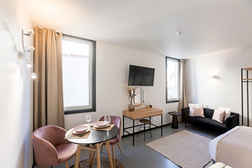 Estúdio moderno no Porto com área de refeições, sofá preto, TV, kitchenette e vista para a cidade