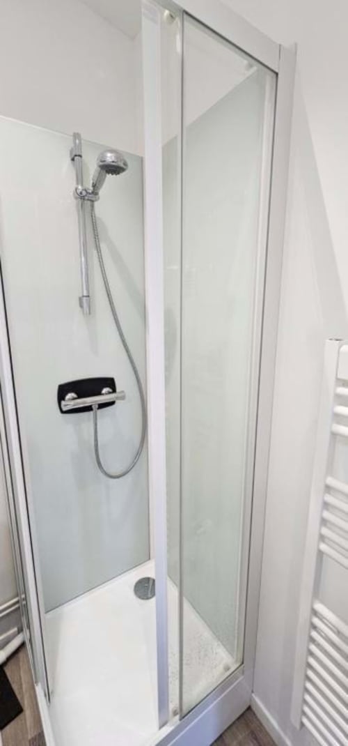 Cabine de douche moderne avec paroi vitrée, robinetterie chromée et carrelage blanc à l'Atelier des Gites Saint Valery En